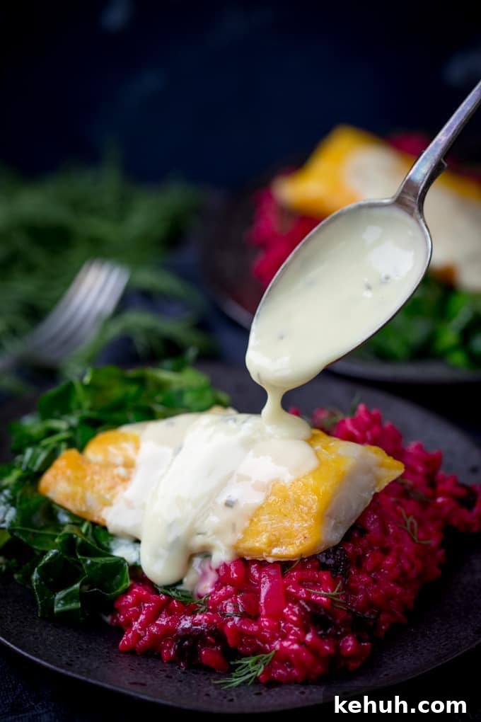 Smoked Haddock with Beetroot Risotto and Garlicky Greens with sauce being poured over from a spoon