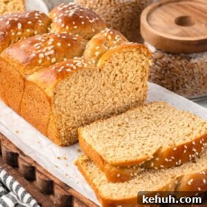 Khorasan (Kamut) Wheat Bread Recipe — Rustic Sourdough Loaf 11 Partially sliced braided Khorasan Wheat Bread with sesame seeds on parchment paper, jars of grains behind.