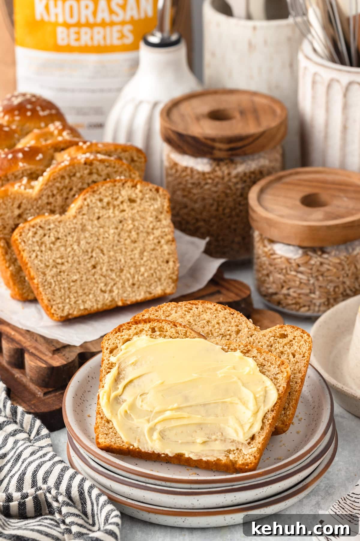 A buttered bread slice on a plate, with sliced bread and Khorasan Berries package behind.