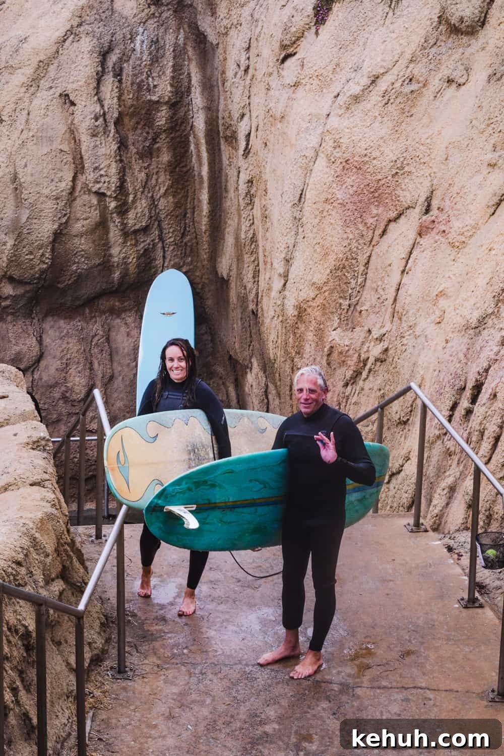 2 surfers on the stairwell in Pleasure Point carrying their surf boards
