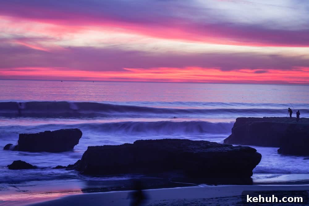 A pink and purple sunset in Santa Cruz over the ocean with waves coming in