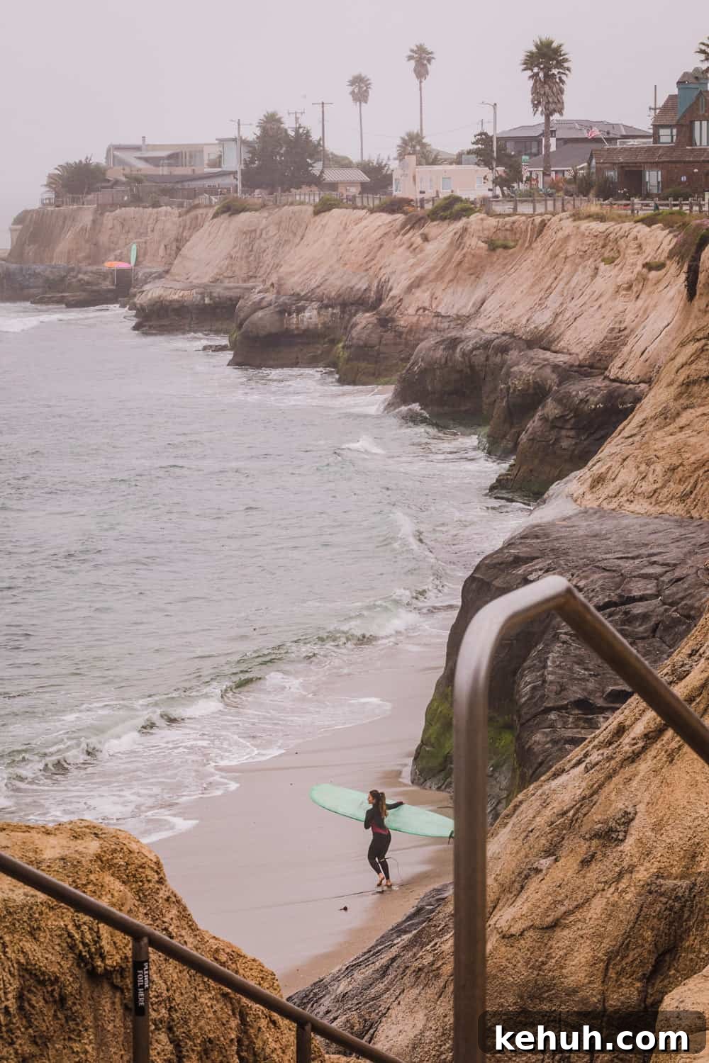A view of Pleasure Point, where the cliffs meet the ocean, and a surfer about to paddle out