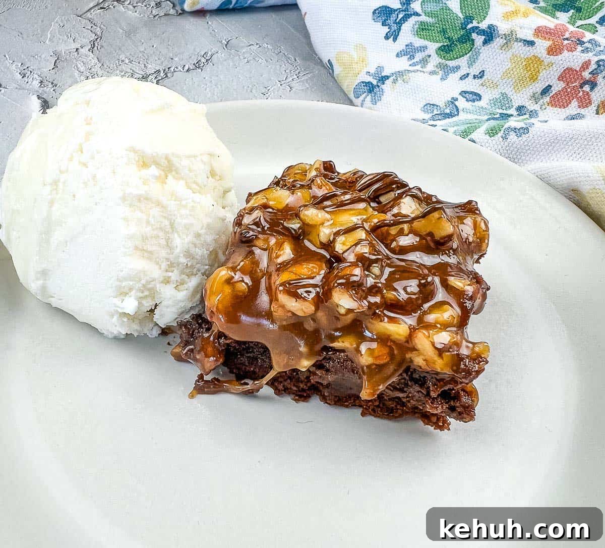 A piece of Turtle Brownie with ice cream on a plate.