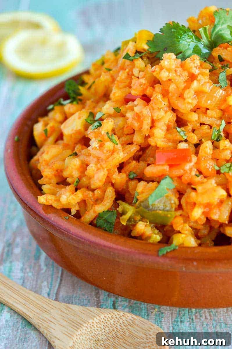 front view of mexican rice in a brown dish with lemon slices in the background
